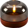 A close-up of a decorative LED candle with a smoky glass dome and a terracotta base. Produktbild-Vorschau
