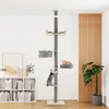 A multi-level cat tree with various platforms and beds, set up in a modern living room with a bookshelf and a plant. Produktbild-Vorschau