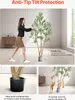 A woman pushing an artificial olive tree to demonstrate its stability, with close-ups of the pot and a dog interacting with the tree. Anteprima dell’immagine prodotto