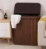 A laundry basket with a towel draped over the side, next to a nightstand and a sofa. Produktbild-Vorschau