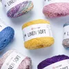 Several skeins of YarnArt Linen Soft yarn in various colors are arranged on a light gray background. Produktbild-Vorschau
