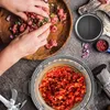 Hands mixing ground meat with onions and herbs in a wooden bowl, with a food processor and chopped red peppers in the foreground. Produktbild-Vorschau
