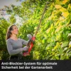 A woman is using a hedge trimmer to trim a bush. Produktbild-Vorschau