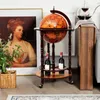 A globe bar cart with wine bottles and a painting in the background. Náhled obrázku produktu