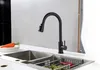 A black kitchen faucet is shown above a stainless steel sink with some vegetables and a carrot on a plate nearby. Anteprima dell’immagine prodotto