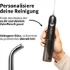 A hand holding a black oral irrigator with text overlays describing its features. Produktbild-Vorschau