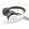 A pair of white and black wireless headphones rests on an open book. Produktbild-Vorschau