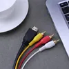 A close-up view of an HDMI cable and three RCA cables on a textured gray surface, with a portion of a laptop and a white cup visible in the background. Voir les images du produit