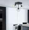 A modern dining area with a black chandelier hanging over a white table set for a meal. Produktbild-Vorschau