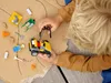 A child playing with LEGO construction vehicles on a cardboard surface with drawn roads. Produktbild-Vorschau
