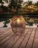 A solar lamp sits on a wooden deck next to a pool, with string lights in the background. Anteprima dell’immagine prodotto