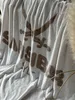 A soft, textured blanket with a graphic print is draped over a surface, with wispy dried grass in the foreground. Produktbild-Vorschau