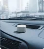 A small, white, cylindrical speaker sits on a car dashboard. Podgląd zdjęcia produktu