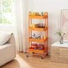 An orange kitchen trolley filled with various items is placed next to a sofa and a cabinet in a room with natural light coming from a window. Náhled obrázku produktu