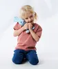 A young girl is kneeling and hugging a blue plush toy rabbit. Náhľad obrázku produktu