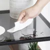 A hand is wiping up a spill on a glass table. Produktbild-Vorschau