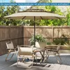 A patio set with a large umbrella and chairs on a wooden deck, surrounded by a wooden fence and greenery. Anteprima dell’immagine prodotto