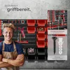 A man is standing in front of a wall-mounted tool organizer filled with various tools and bins. Náhled obrázku produktu