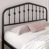 A black metal bed frame with a decorative headboard and pillows on a bed. Podgląd zdjęcia produktu