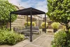 A modern backyard patio with a black pergola, sectional sofa, and potted plants. Produktbild-Vorschau