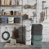 A collection of storage bins and household items neatly arranged against a rustic wooden wall. Produktbild-Vorschau