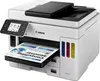 A white and black Canon MAXIFY GX 7050 Multifunction Printer is shown from a slightly elevated front-left angle, with a document partially printed and emerging from the paper tray. The printer has a color touchscreen display on the left and visible ink tan Produktbild-Vorschau
