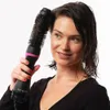 A woman is using a Revlon hair dryer and volumizer on her hair. Voir les images du produit