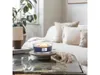 A lit candle sits on a coffee table in a living room setting. Podgląd zdjęcia produktu