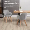 Two gray dining chairs with wooden legs are placed in a dining room setting next to a wooden dining table. Podgląd zdjęcia produktu