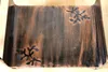 A close-up overhead view of a decorative metal firewood rack with a rustic, distressed finish and cut-out floral designs. Podgląd zdjęcia produktu