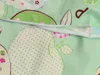 A close-up view of a green baby bedding with a pattern of apples and small flowers, featuring a zipper. Náhľad obrázku produktu