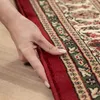 A hand is shown touching the edge of a rug. Produktbild-Vorschau
