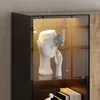 A close-up view of a display cabinet with a white bust and a silver flower decoration. Produktbild-Vorschau