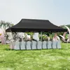 A black party tent set up outdoors with tables and chairs covered in white cloths, decorated with flowers and large pink ribbon-like structures. Náhled obrázku produktu