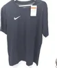 A black Nike t-shirt with a white Nike logo on the chest, hanging on a hanger against a white background. A product tag is attached to the collar. Produktbild-Vorschau