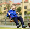 A young boy is happily swinging on a wooden swing set outdoors. Náhled obrázku produktu