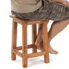 A person sitting on a wooden stool. Produktbild-Vorschau