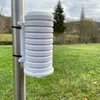A white weather sensor shield mounted on a metal pole in a grassy outdoor area. Voir les images du produit