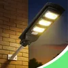 A solar street lamp is mounted on a brick wall, illuminated against a twilight sky. Anteprima dell’immagine prodotto