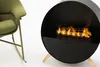 A modern black fireplace with a realistic flame effect is shown next to a green armchair. Náhled obrázku produktu