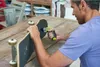A man is using a power drill to work on a skateboard. Voir les images du produit