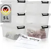 A stack of clear plastic storage boxes with black lids and clips, some containing small items. A label with German text and a German flag logo is visible on the left. Produktbild-Vorschau