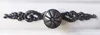 A close-up shot of a decorative metal handle on a white surface. Produktbild-Vorschau