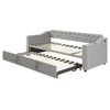 A gray upholstered daybed with a pull-out trundle bed extended. Produktbild-Vorschau