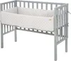 A grey crib with a white quilted bumper pad. Produktbild-Vorschau
