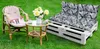 A cat is resting on a chair next to a small table with flowers, with a pallet sofa in the background, all on a grassy lawn. Produktbild-Vorschau