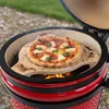 A pizza is being cooked on a pizza stone inside a red ceramic grill. Produktbild-Vorschau