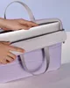 Hands placing a laptop into a purple laptop bag. Náhľad obrázku produktu