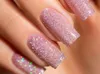 A close-up shot of a hand with several nails painted with a glittery pink gel polish. Voir les images du produit