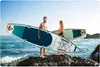 A couple holding stand-up paddleboards on a rocky shore with the ocean in the background. Náhled obrázku produktu